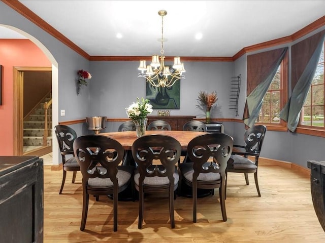 dining room with crown molding, light wood-style floors, stairway, a chandelier, and arched walkways