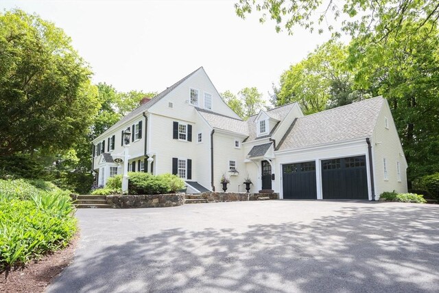 view of front of home featuring a garage, driveway, and roof with shingles