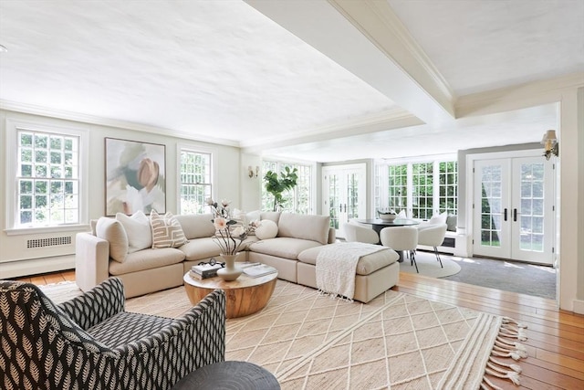 living area featuring beam ceiling, ornamental molding, a baseboard heating unit, french doors, and light wood finished floors