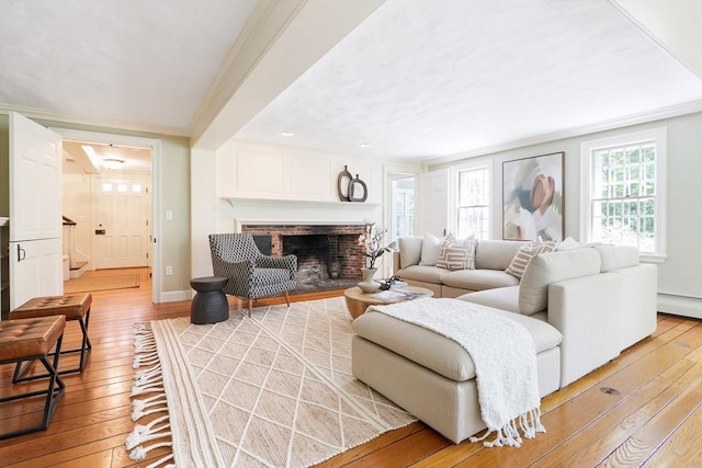 living area featuring light wood-type flooring, ornamental molding, baseboards, baseboard heating, and a brick fireplace