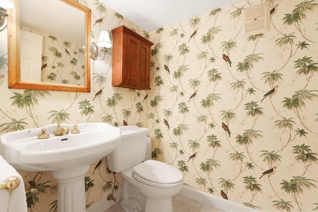 half bath with wallpapered walls, toilet, baseboards, and a sink