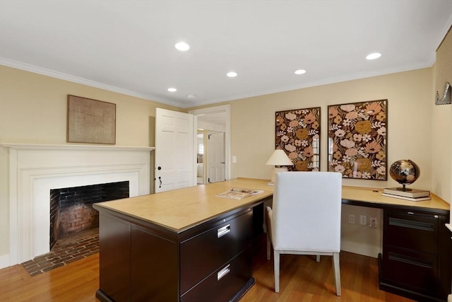 home office with a fireplace with flush hearth, crown molding, and wood finished floors