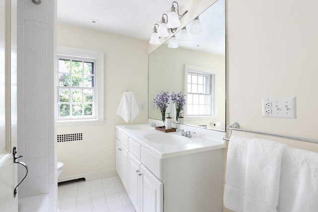 full bath with a sink, baseboards, toilet, and double vanity