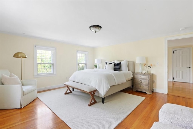 bedroom with crown molding, baseboards, and light wood finished floors