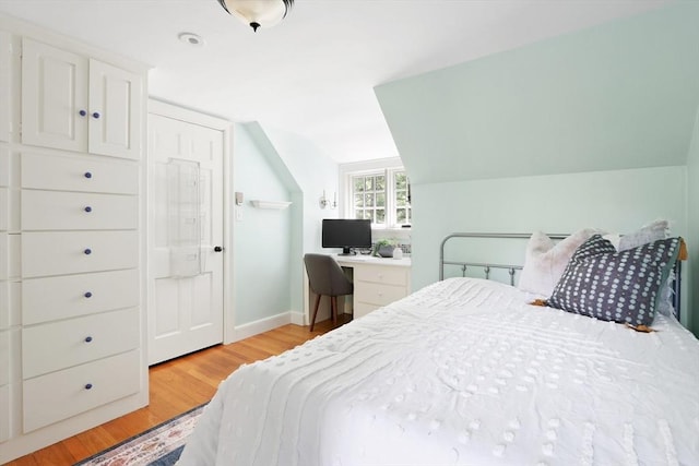 bedroom with light wood-type flooring, baseboards, and lofted ceiling