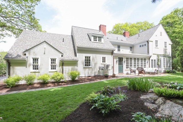 back of house featuring a patio, a yard, a chimney, and a shingled roof