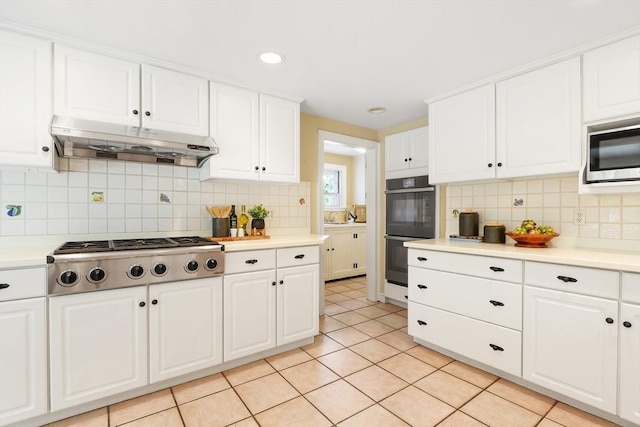 kitchen with light tile patterned floors, light countertops, white cabinets, appliances with stainless steel finishes, and under cabinet range hood