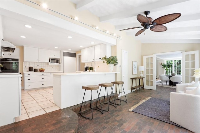 kitchen featuring backsplash, white cabinetry, french doors, a peninsula, and built in appliances