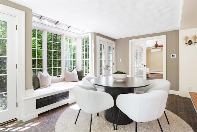 dining space with baseboard heating, french doors, baseboards, and brick floor