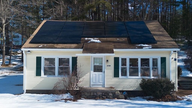 view of front facade featuring roof with shingles and solar panels