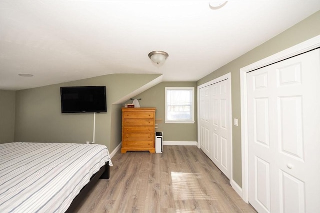 bedroom featuring light wood-style floors, vaulted ceiling, and baseboards