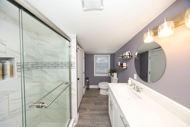 bathroom with toilet, a stall shower, wood finished floors, and vanity