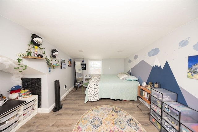 bedroom featuring a fireplace, wood finished floors, and baseboards