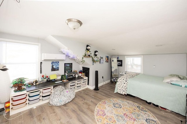 bedroom featuring a wall mounted air conditioner, wood finished floors, and baseboards