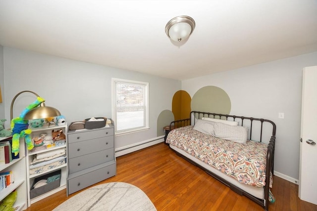 bedroom with a baseboard heating unit, baseboards, and wood finished floors