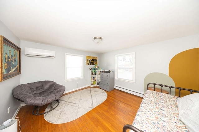 bedroom featuring a baseboard heating unit, a wall mounted air conditioner, baseboards, and wood finished floors