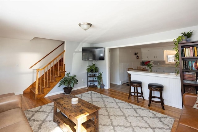 living room featuring stairs, baseboards, and wood finished floors