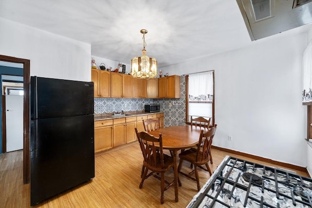 kitchen with freestanding refrigerator, stainless steel microwave, a sink, and light wood-style floors