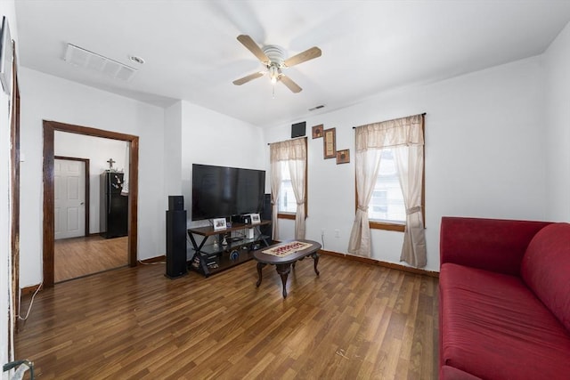 living area featuring wood finished floors, a ceiling fan, and baseboards