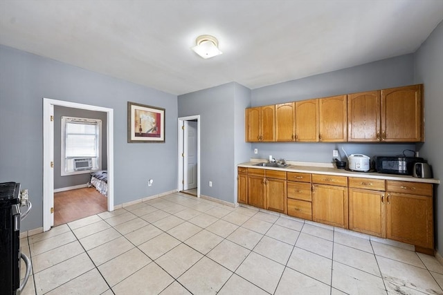 kitchen with light countertops, light tile patterned flooring, a sink, brown cabinets, and baseboards