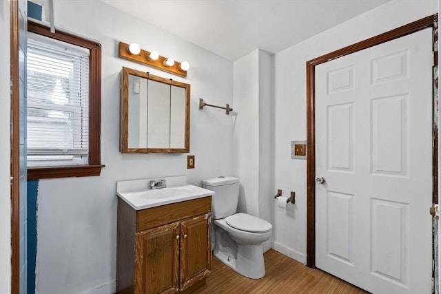 bathroom with toilet, wood finished floors, vanity, and baseboards