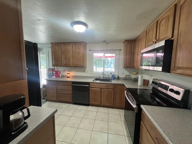 kitchen with black appliances, brown cabinets, light tile patterned flooring, and a sink