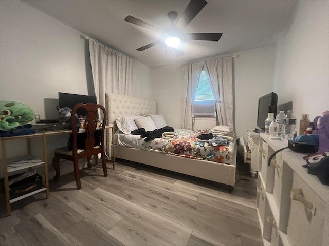 bedroom with light wood-style flooring, a ceiling fan, and cooling unit
