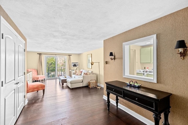 living area featuring baseboards, dark wood-style flooring, and a textured ceiling