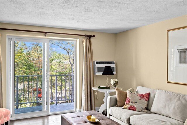 living area with wood finished floors, a textured ceiling, and a wall unit AC