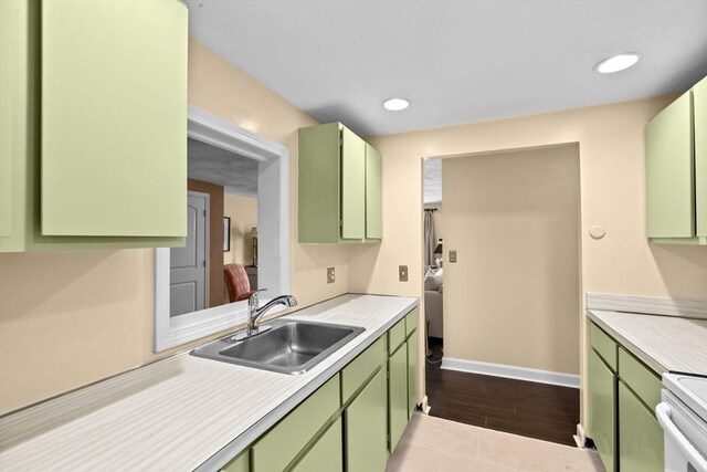 kitchen with baseboards, a sink, green cabinetry, and light countertops