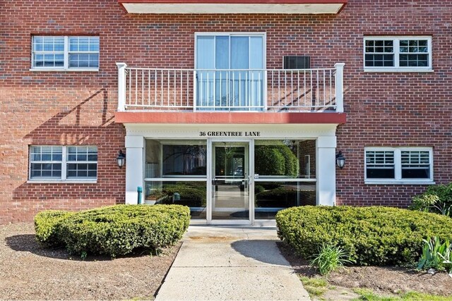 entrance to property with brick siding and a balcony