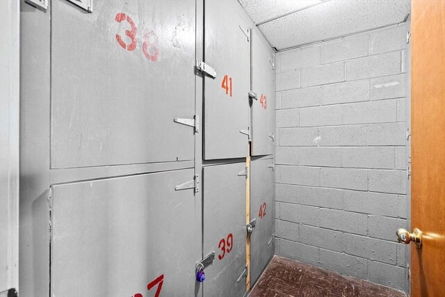 interior space featuring concrete block wall and a drop ceiling