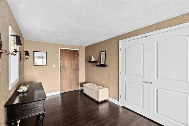 entrance foyer featuring dark wood-type flooring, a textured ceiling, and baseboards