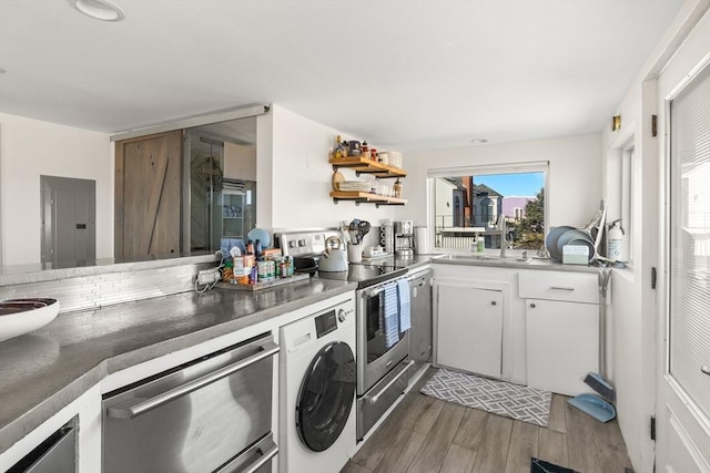 kitchen with white cabinets, open shelves, appliances with stainless steel finishes, washer / dryer, and wood finished floors