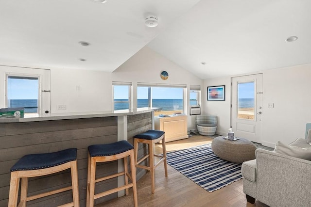 living room featuring a water view, light wood-type flooring, and lofted ceiling