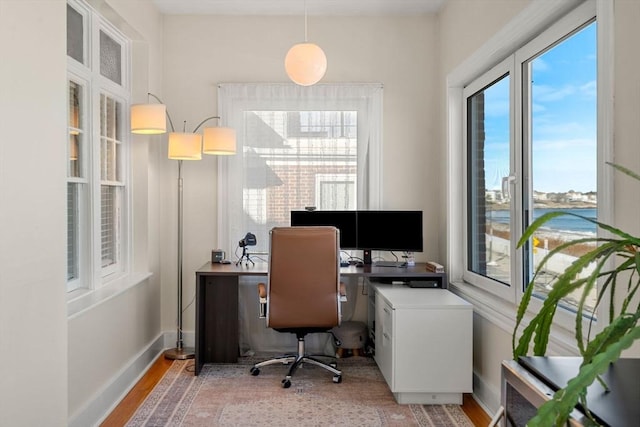 home office with a healthy amount of sunlight and light hardwood / wood-style flooring