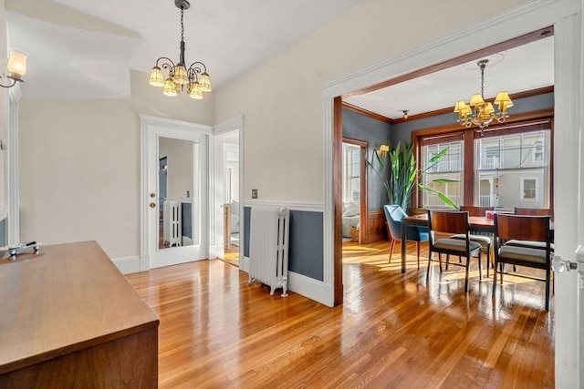 foyer entrance with wood-type flooring, a notable chandelier, and radiator heating unit