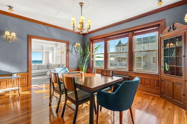 dining room featuring crown molding, a chandelier, and light hardwood / wood-style flooring