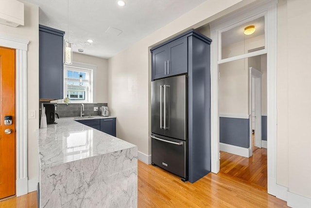 kitchen with light wood-type flooring, light stone countertops, sink, and high end fridge