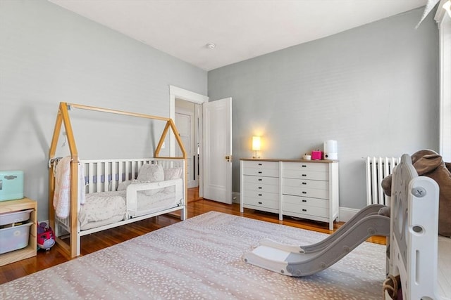 bedroom featuring hardwood / wood-style floors and radiator heating unit