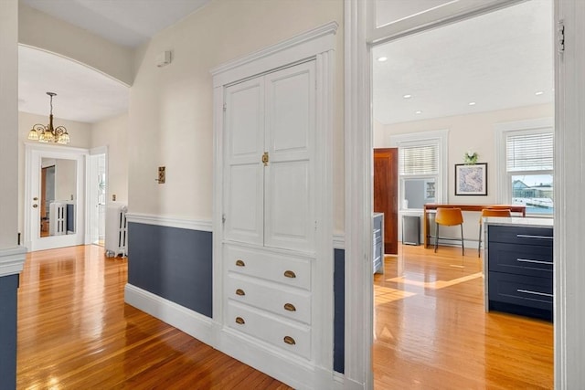 hall featuring a chandelier and light hardwood / wood-style floors