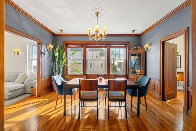 dining room with hardwood / wood-style floors, ornamental molding, and a notable chandelier