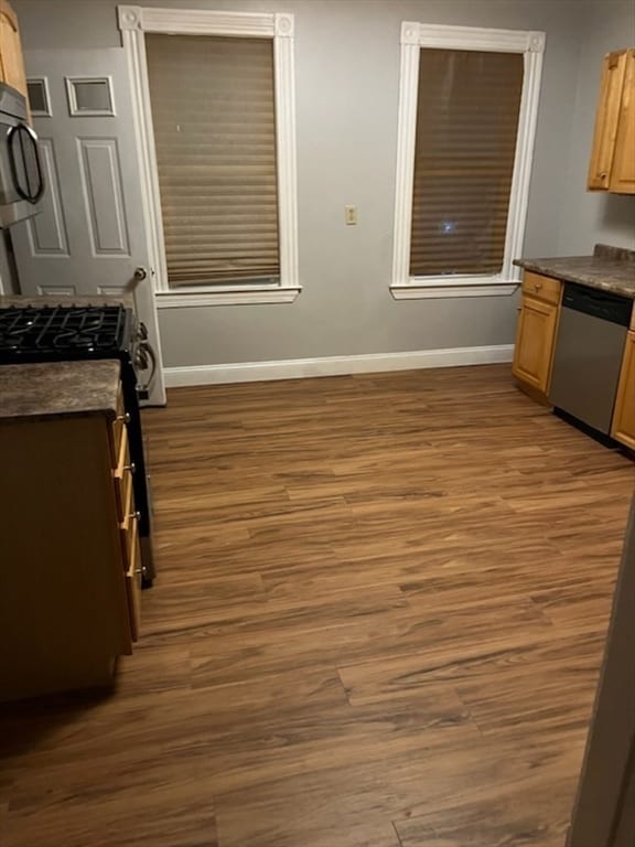 kitchen featuring dark hardwood / wood-style flooring, stainless steel dishwasher, and light brown cabinets