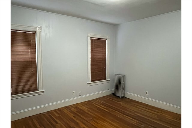 unfurnished room with radiator heating unit and dark hardwood / wood-style flooring