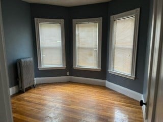 spare room featuring wood-type flooring and radiator heating unit