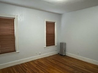 unfurnished room featuring radiator heating unit and dark hardwood / wood-style flooring