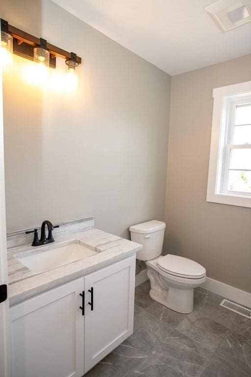 half bathroom with toilet, vanity, and baseboards