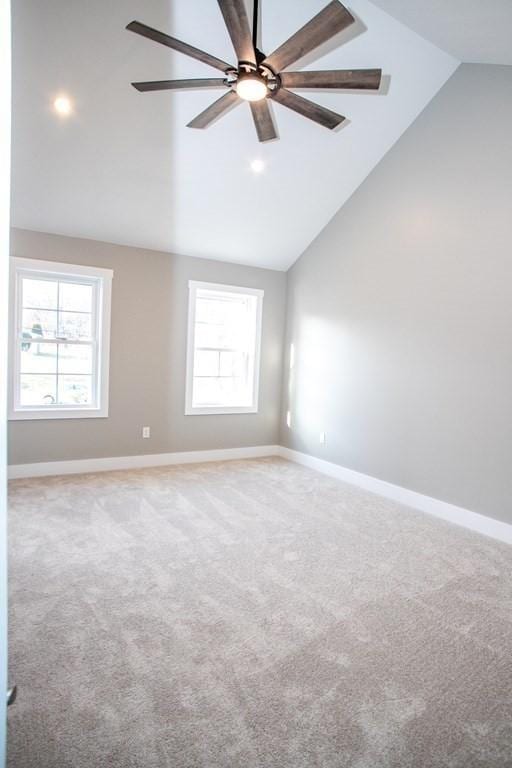 carpeted empty room with lofted ceiling, baseboards, and ceiling fan