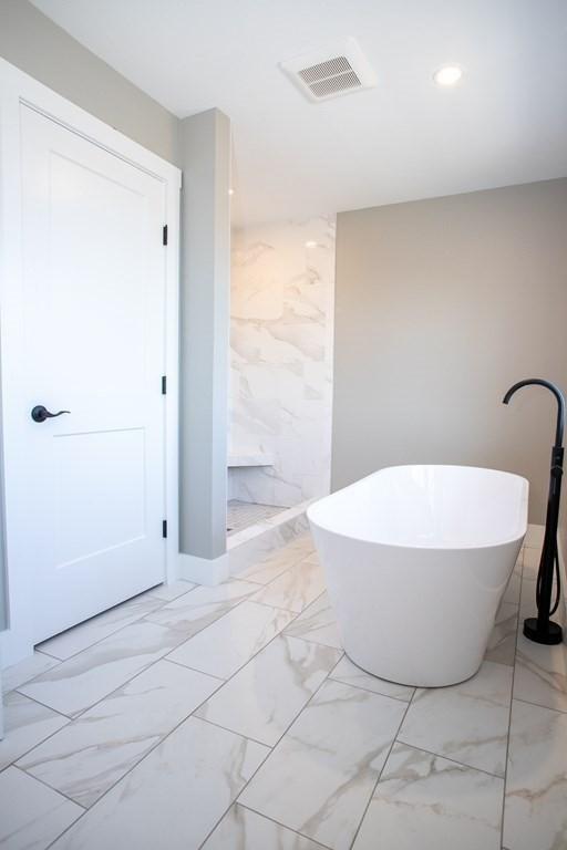 bathroom featuring marble finish flooring, a soaking tub, recessed lighting, and a shower