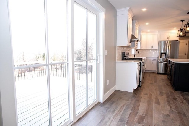 kitchen with appliances with stainless steel finishes, light countertops, decorative backsplash, dark wood finished floors, and white cabinets